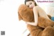 A woman is hugging a large teddy bear on a bed.