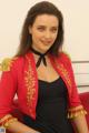 A woman in a red jacket sitting on a red couch.