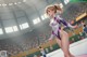 A woman in a purple leotard standing on a gymnastics mat.