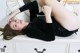 A woman laying on top of a dresser next to a mirror.