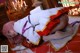 A woman in a white and red outfit laying on a bed.