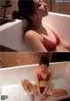 A woman in a red bikini sitting in a bathtub.