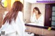 A woman in a bathrobe looking at herself in the mirror.