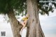 A woman leaning against a tree on the beach.