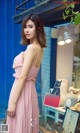 A woman in a pink dress standing in front of a store.