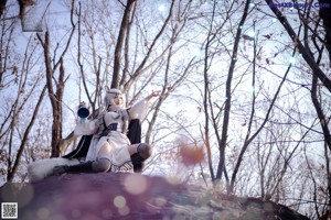 A woman sitting on top of a rock in the woods.